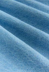 Himmelblauem Stoff mit einer weichen, strukturierten Oberfläche, der dezente Webmuster und sichtbare Dehnbarkeit aufweist, in sanften, fließenden Falten drapiert.