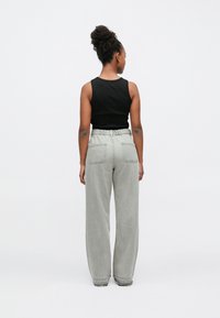 Čierny tielkový top a svetlosivé široké nohavice s elastickým pásom a dvoma zadnými vreckami, zobrazené zozadu.