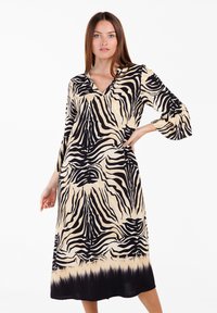 Vestido negro y beige con un diseño de estampado de cebra, con escote en V, mangas largas y una silueta fluida que llega hasta la mitad de la pantorrilla.