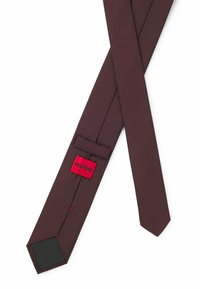 Cravatta in seta bordeaux con una sottile trama a costine, larghezza ridotta e un'etichetta rossa con il marchio "HUGO" e la scritta "MADE IN ITALY".