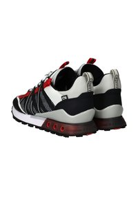 Sneaker mit einem Obermaterial aus schwarz-weißer Maschenstruktur, roten Akzenten und einer grauen Zwischensohle. Mit einem gepolsterten Kragen und einer strukturierten Gummisohle mit hexagonalen Ausschnitten.