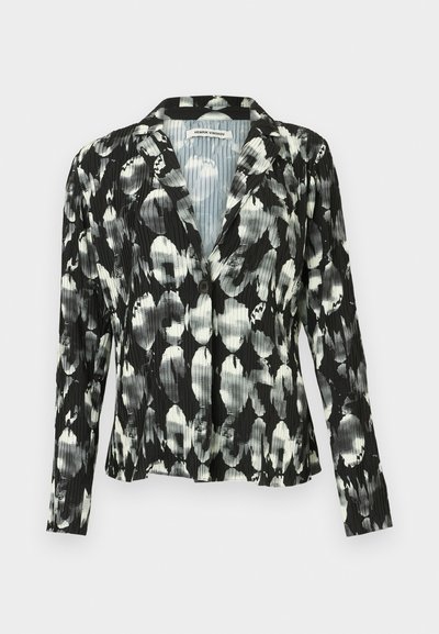 Μαύρο και λευκό πλισέ σακάκι με λουλουδάτο σχέδιο, κούμπωμα με ένα κουμπί, γιακά με άνοιγμα και μακριά μανίκια. Λεπτομέρεια υφής υφάσματος.