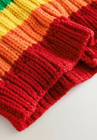 Gebreide trui met levendige horizontale strepen in groen, geel, oranje en rood, met een chunky geribbelde textuur aan de zoom.