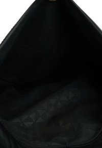 Zwarte binnenkant van een tas, met een gladde textuur en een subtiel geometrisch patroon van driehoeken. Ritsopening aan de bovenkant.