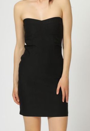 Vestido mini negro sin tirantes ajustado en la cintura, llevado por una persona de pie con los brazos relajados a los lados, frente a un fondo liso.