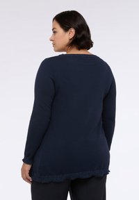 Marineblaue Langarmpullover mit strukturiertem gewelltem Saum und Ausschnitt. Aus einem weichen Strickmaterial gefertigt. Die Rückansicht zeigt einen taillierten Schnitt.