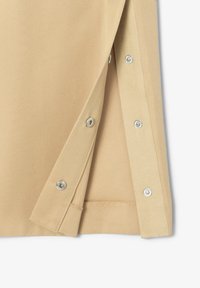 Tissu en coton beige avec une texture lisse, doté de boutons-pression argentés le long du bord et d'un ourlet net. Conçu avec une ouverture pliée.