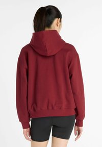 Burgundy hoodie with a spacious hood, dropped shoulders, and ribbed cuffs. Cotton blend fabric offers a soft texture and relaxed fit.