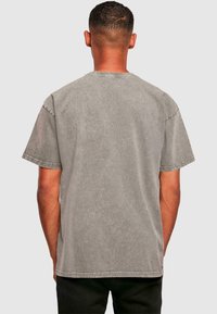 Graues Kurzarm-T-Shirt mit lockerer Passform, das eine abgenutzte Textur und genähte Säume aufweist. Keine sichtbaren Grafiken oder Drucke.