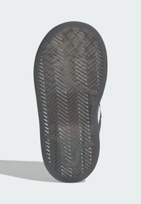 Sole of a black shoe with translucent rubber featuring a zigzag tread pattern against a white background.