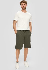 T-Shirt aus Baumwollmischung in Weiß und olivgrünen Baumwollshorts mit elastischem Bund, Seitentaschen und Kordelzugdetails. Sneaker sind enthalten.