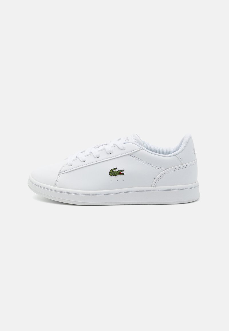 Hvite sneakers med en glatt syntetisk overdel, rund tå, snøring foran og grønt krokodille-logo på siden. Enkel, klassisk design.
