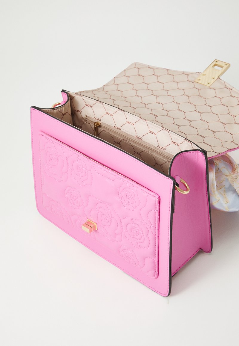 Różowa skórzana torebka z tłoczonym kwiatowym wzorem i zapięciem w kolorze złota. Wnętrze pokryte wzorem z logo, zawiera kieszeń na zamek.