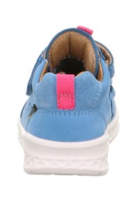 Niebieski sneaker z aksentami z zamszu, różową pętelką i białą teksturowaną podeszwą. Posiada rzepy i wyściełaną kostkę dla wygody.