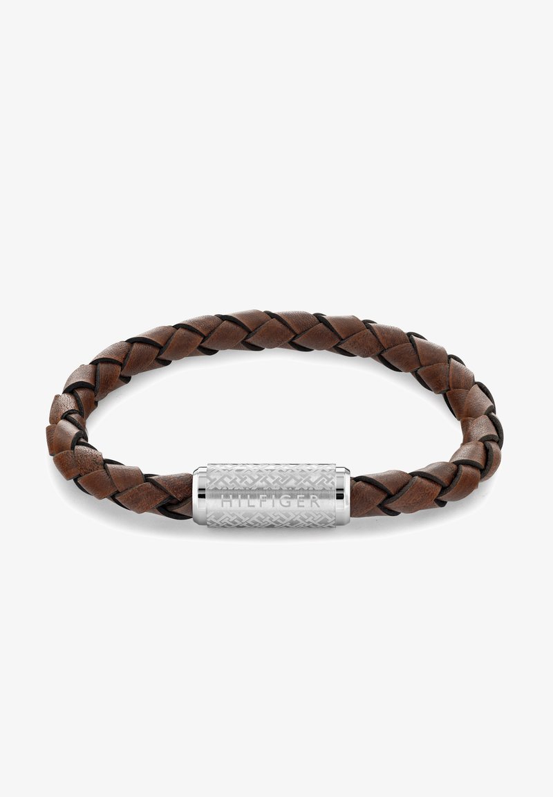 Bruine leren armband met vlechtwerk, voorzien van een gestructureerde zilveren sluiting met de gravure "HILFIGER." Glad en duurzaam materiaal.