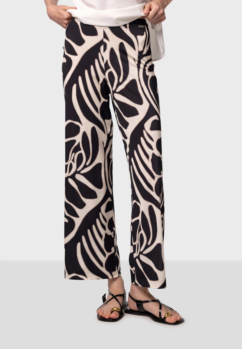 Des pantalons larges à motifs noir et beige présentent un design floral, fabriqués dans un tissu doux avec une texture lisse et une taille élastique.