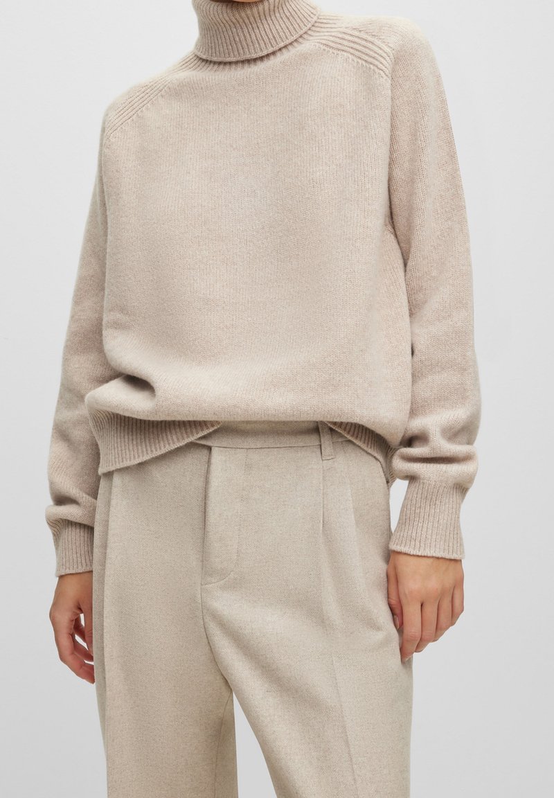 Beige polotröja med ribbad ärm- och nederkant. Mjuk textur, avslappnad passform, i kombination med beige skräddarsydda byxor. Minimalistisk design.