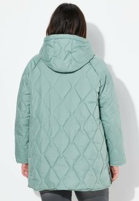 Vadderad jacka i ljus mintgrön. Diamantmönstrat kviltat mönster, huva, långa ärmar och sidofåttor vid nederkanten. Snygg textur.