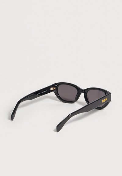 Lunettes de soleil rectangulaires noires avec verres foncés, ornées du texte « Angels » en doré sur une branche, présentées sur une surface blanche.