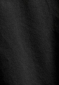 Gros plan sur un tissu noir texturé avec un motif de tissage diagonal et des plis doux.