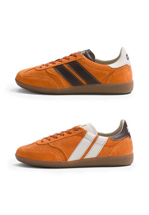 Paire de baskets en suède orange avec des bandes latérales marron et blanches, semelles en gomme et design à lacets vues de profil.
