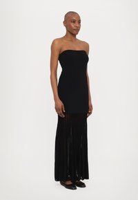 Black strapless dress with a fitted bodice and flowing pleated skirt. Material appears smooth with a sheer layered lower section.