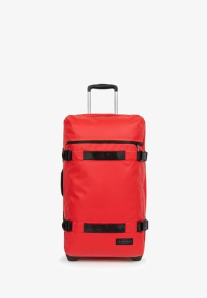 Valigia a rotelle rossa in tessuto con cinturini e dettagli neri, dotata di un manico telescopico e una chiusura con cerniera nella parte superiore.