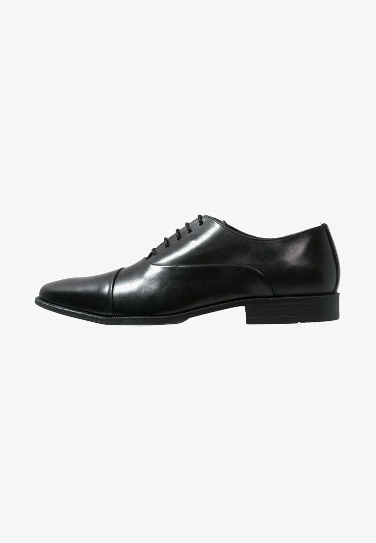 Chaussure de ville en cuir noir avec un bout pointu, six œillets pour les lacets, texture lisse et un talon bas. Design simple et classique.