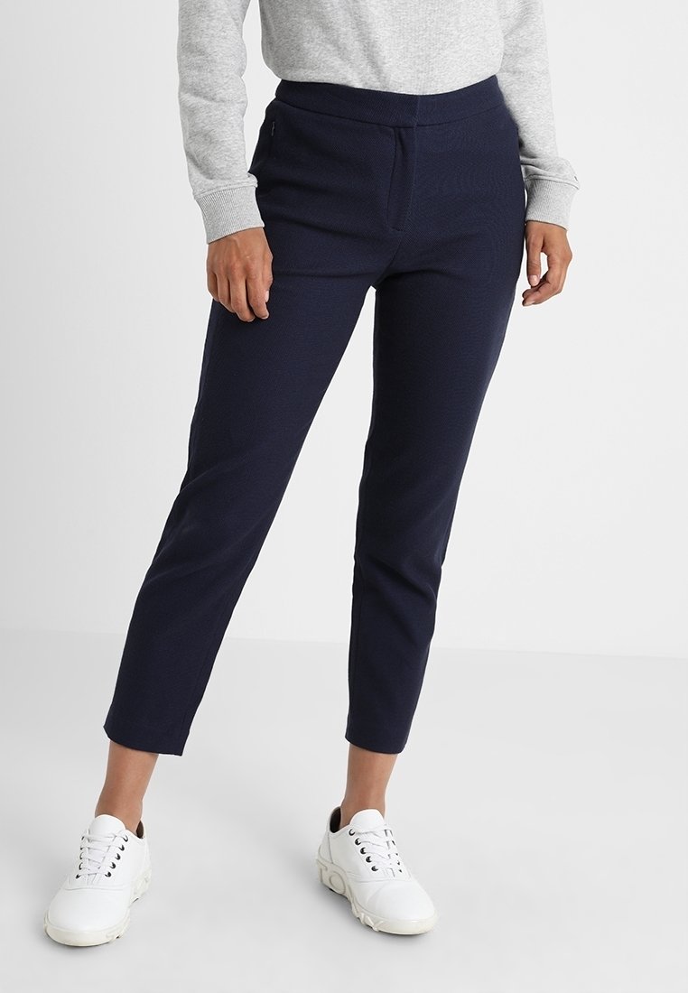 Pantalon bleu marine, fuselé avec un motif texturé et une taille élastique. Associé à des baskets blanches pour un look décontracté.