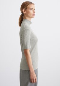 Siv, rebrast, kratkosleevni turtleneck z medeničnim dizajnom, gladko teksturo in klasično silhueto, v kombinaciji s sivo krilom.
