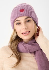 Paarse geribbelde gebreide beanie met een rood hartlogo, gecombineerd met een bijpassende paarse sjaal met franjes. Zacht textielmateriaal.