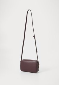 Geantă crossbody burgundă cu o curea lungă și reglabilă, având o formă rectangulară și o textură netedă, așezată pe un fundal alb.