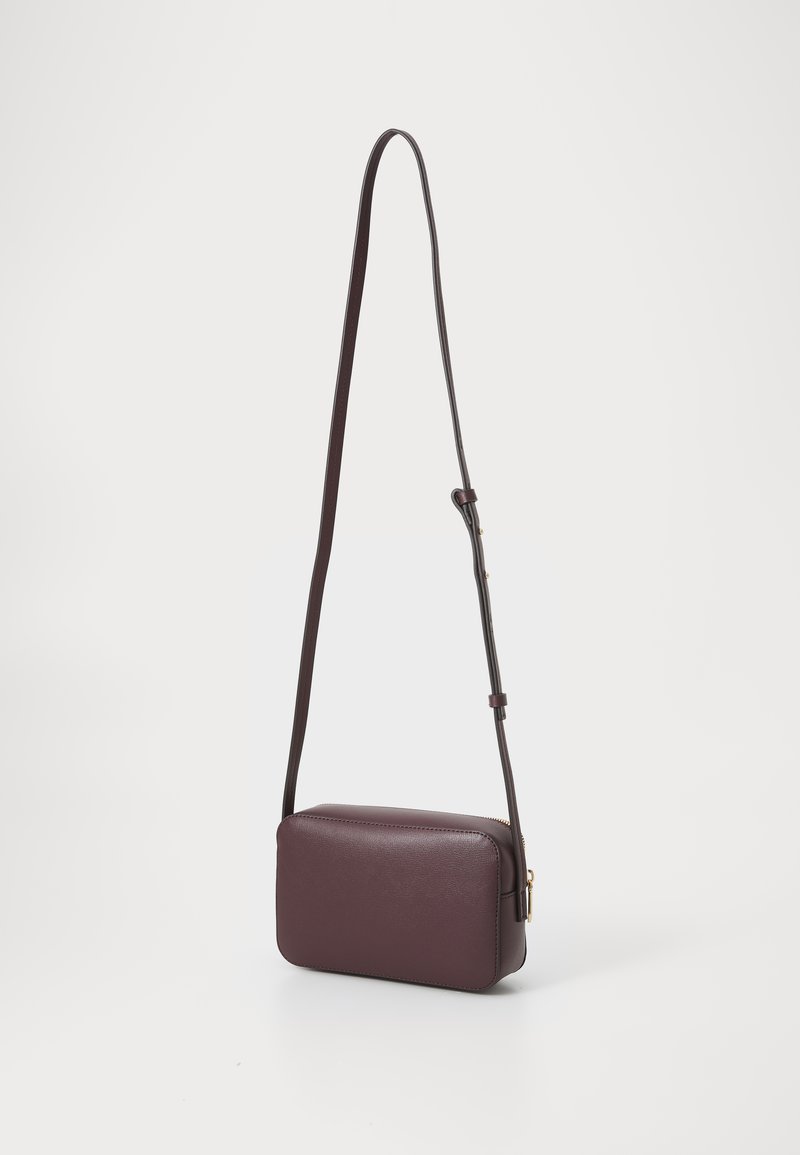 Borsa crossbody bordeaux con una lunga tracolla regolabile, caratterizzata da una forma rettangolare e una texture liscia, posizionata su uno sfondo bianco.