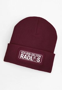 Maroon knit beanie with ribbed texture, featuring a white rectangular patch that reads "ICH BIN SELTEN RADLOS" along with a bike icon.