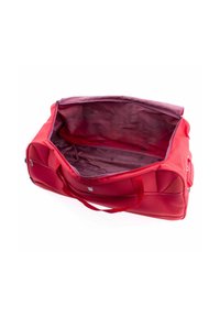 Sac de sport rouge avec doubles poignées, fermeture éclair et extérieur uni. Intérieur doublé de violet avec un motif subtil, spacieux et non structuré.