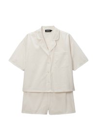 Ensemble de pyjama beige clair à manches courtes comprenant une chemise boutonnée avec une poche et un short assorti, fabriqué dans un tissu doux et texturé.