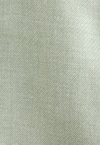 Textured fabric in a pale green shade, featuring a woven pattern with distinct fibers, offering a soft and durable surface.