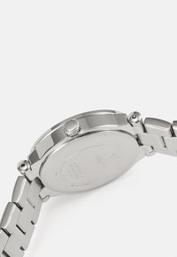 Orologio in acciaio inox argentato, con cassa tonda, ghiera testurizzata e cinturino a maglie. Manopola laterale per le regolazioni. Retro incassato.