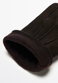 Guanto in suede marrone con polsino a maglia marrone scuro. Il design presenta dettagli di cucitura discreti lungo le dita per un tocco di texture in più.