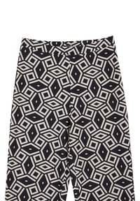 Pantaloni con motivo bianco e nero a design geometrico, caratterizzati da diamanti e esagoni, realizzati in un tessuto liscio.