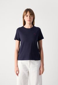 T-shirt en coton bleu marine avec un col rond et des manches courtes ; présente un petit logo bordeaux sur la poitrine. Texture douce, coupe décontractée.