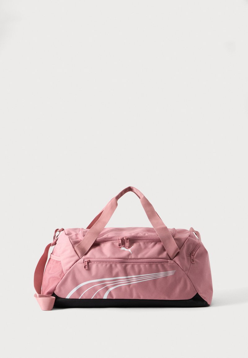 Ροζ αθλητική τσάντα τύπου duffel με διπλές λαβές, μπροστινή τσέπη με φερμουάρ, δίχτυ στη μία πλευρά και λευκό λογότυπο Puma και ρίγες σε ανοιχτό φόντο.