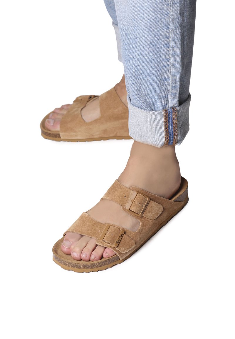 Sandales en daim beige avec deux boucles ajustables, semelle intérieure anatomique et semelle texturée. Portées avec un jean en denim clair retroussé.