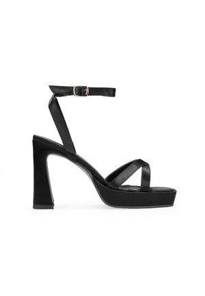 Sandalias de tacón alto negras con plataforma y tira en el tobillo. Presentan finas tiras cruzadas y un tacón sólido y grueso. Están hechas de un material suave.