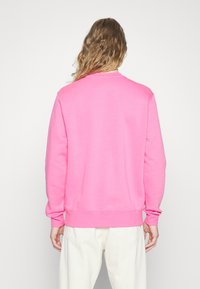 Fleece-pullover i klar rosa, med långa ärmar och rundad halsringning. Slät yta med ribbade muddar och midja.