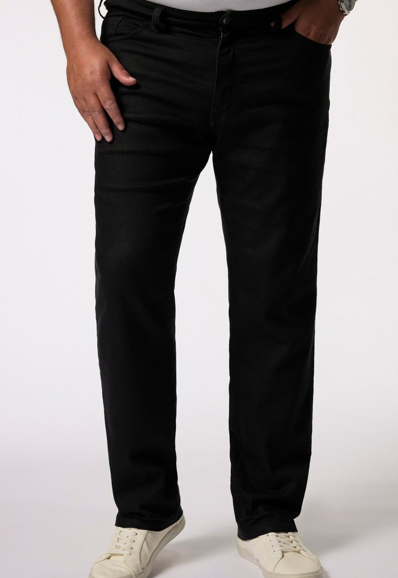 Jean en denim noir avec une coupe droite, présentant une taille classique et des coutures visibles, associés à des baskets blanches.