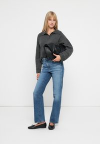 Grå cropped genser med krage, løse blå jeans og svarte leiligheter. Holder en svart lærclutch. Enkel, uformell antrekk.