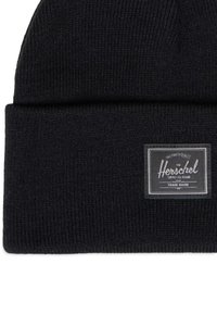 Mustakudottu, kaksinkertainen pipolakki, jossa on suorakulmainen Herschel Supply Co. -kangaslogo lapussa. 
