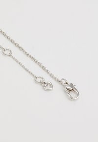 Ασημένια αλυσίδα κολιέ με διασυνδεδεμένους κρίκους, κρεμαστό φυλαχτό καρδιάς και κλείσιμο με γάντζο. Λείο υφή με γυαλιστερή φινέτσα.