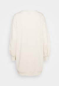 Vaalean kermaisen värinen collegepaita, jossa on pitkät, puffimaiset hihat ja väljä istuvuus. Sisältää ribbien ympärysjohtuen ja helman tuen. Sujuva, pehmeä kangas.